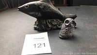 Photo of both black fish figurine and small owl figurine placed on table with auction tag 121