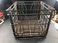 Full view of the metal milk crate showing wire frame and rust.