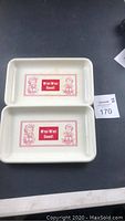 Two vintage cream-colored rectangular trays placed side by side on a black surface with red Campbell Soup design