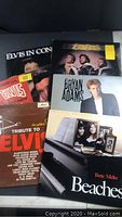 Photo showing six vinyl record albums stacked, including Elvis Presley, Bee Gees, Bryan Adams, Bette Midler.