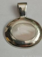 Close-up front view of oval silver pendant with natural pearl-colored moonstone.