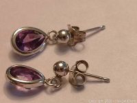 Close-up photo of one silver amethyst earring showing teardrop faceted amethyst stone and post with butterfly clasp.