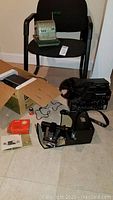 Green metal adding machine on black chair, cardboard boxes and film equipment on floor