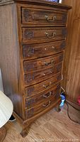 Full front view of wooden lingerie chest showing 8 drawers with brass handles and carved details. Some handles and hardware are missing.