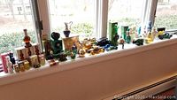 Full view of multiple Avon cologne bottles displayed on windowsill, various shapes and colors.