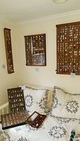 Wide view of bedroom wall and bed showing multiple mounted wooden shadow boxes filled with thimbles