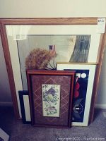 Photo of all four framed prints leaning against a wall, showing different frames and a visible American flag reflection in glass.