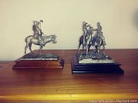 Front view of both pewter sculptures side by side on wooden bases
