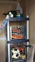 Plastic shelving unit with crates holding extension cords, American flags, and cleaning supplies.