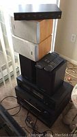 Stacked stereo components including Harman Kardon tuner, CD player, Onkyo cassette player, and bookshelf speakers from Polk Audio and AIWA.
