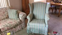 Photo showing the striped wingback armchair with vertical green and white stripes, and part of the glass coffee table
