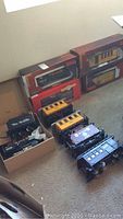 Four original boxed cars displayed with loose rolling stock on carpet