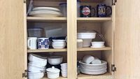 Cabinet with white ceramic dishes, bowls, mugs, ramekins, and Pyrex glass baking dishes