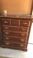 Full view of wooden dresser showing all five drawers, brown finish, brass handles