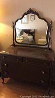 Front view of the full vintage wooden dresser with attached ornate mirror, showing wood finish, drawer handles, and overall structure.