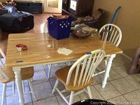 Photo of wooden kitchen table with natural wood top and white legs showing table with chairs and items on it (not included).