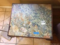 Top view of the marble side table showing the multicolored, mottled marble surface with tags affixed.