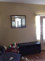 Wall-mounted wood-framed mirror above a dark wood credenza, showing size and placement in room