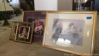 Four framed art pieces arranged on carpet, varying sizes and floral and landscape themes