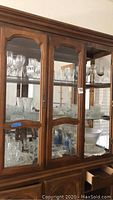 Wooden cabinet with three shelves filled with various crystal stemware, cut glass platters, glasses, and containers.