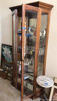 Curio cabinet front and open door showing glass shelves and items inside