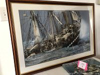 Framed print of the sailing ship Le Siecle du Belem with the book Seapower beneath it on a table.