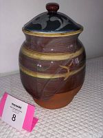 Front view of glazed pottery cookie jar with decorative motifs and lid knob.
