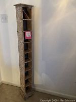 Full view of tall wooden CD tower shelf with carved folk art patterns, showing its slim profile and multiple compartments