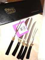 Full set of 5 carving cutlery pieces with black handles and gold plated accents, displayed on a white cloth with the Peeredge Sheffield presentation box behind.