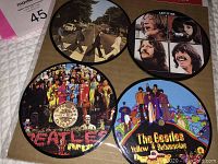 Four round coasters depicting The Beatles album covers: Abbey Road, Let It Be, Sgt. Pepper's Lonely Hearts Club Band, and Yellow Submarine, still in original packaging.