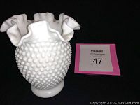 White milk glass vase showing hobnail texture with ruffled edge top in front view against black background with auction lot card.