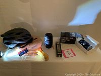 Full view of lot including bike helmet, paddles, lenses, and laces box on table.