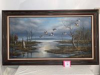 Full view of the large framed landscape painting with flying geese and water scene.
