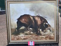 Front view of large painting showing bull in side profile with textured brown and cream background in silver frame with beige linen mat.