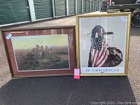 Pair of framed Native American themed pictures, one by J.D. Challenger with a gold frame, and the other by Russell with a reddish-brown frame, displayed outdoors.