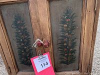 Close-up of the cabinet doors showing hand painted floral design on each panel and round wooden knobs tied with string.