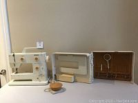 Bernina Nova 900 sewing machine placed on table along with open hard shell carrying case showing storage compartments inside.