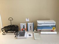 All lot items together on a table, including vacuum bag sealer, cordless phones, USB hub, carry caddy, instructions and vacuum bags.