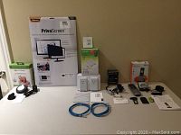 Photo displaying entire lot on a table, showing all five items: Fellowes PrivaScreen privacy filter, Pocket Finder GPS tracker box, TP-Link powerline kit box with two adapters, Digiwave preamplifier box with small device, and AT&T DECT phone handset with charging base and accessories.