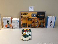 Full lot overview showing all items on table including DeWalt screwdriving set, TP-Link Wi-Fi extender, AT&T handsets, and Stanley gloves.