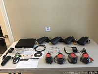 Photo showing four black metal bullet-style security cameras, cables, DVR unit and various accessories layout on table.