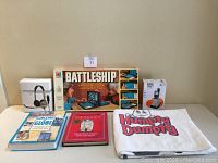Full lot including Battleship game box, 2 children's books, Humpty Dumpty beach towel, AT&T handset box and Koss headset box on table.