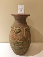 Full view of the vase showing the overall shape, color, and the positioning of the butterfly and floral relief designs.