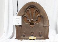 Front view of the Windsor Limited Edition 1932 antique replica radio showing arched wooden body, decorative fleur-de-lis grille, three control knobs, and central dial.