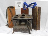 Front and side view of decorative cast iron stove alongside three wooden galloping horse noise maker blocks with rope handles.