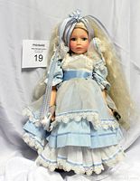 Full front view of the 13-inch Alice in Wonderland doll showing detailed blue and white lace dress, bonnet with ribbons, and long blond hair.