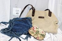 Four purses laid out on white cloth: beige Rosetti fabric purse with brown handles, blue fringed denim purse with metal eyelets, floral tapestry coin purse, large beige textured purse labeled Berlin