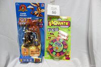 Photo showing both the 1998 Wile E. Coyote & Road Runner Candy Hander motorized candy dispenser in blue packaging and the 1996 Power PEZ Candy Dispenser in green packaging, both sealed and brand new.