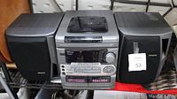 Onkyo AM/FM stereo system with CD and cassette player and two separate speakers shown front view. Visible details include CD player on top, cassette deck below, control buttons, and label indicating 40w x 40w power output.