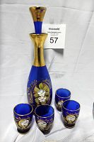 Cobalt blue Bohemian Czech liquor decanter with gold neck and stopper, surrounded by four matching shot glasses with gold and floral hand painting